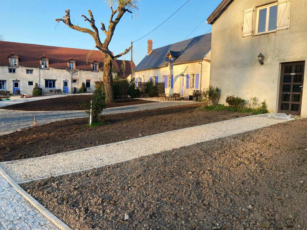Cour de ferme avec un cheminement en gravier traversant des surfaces de terre préparée