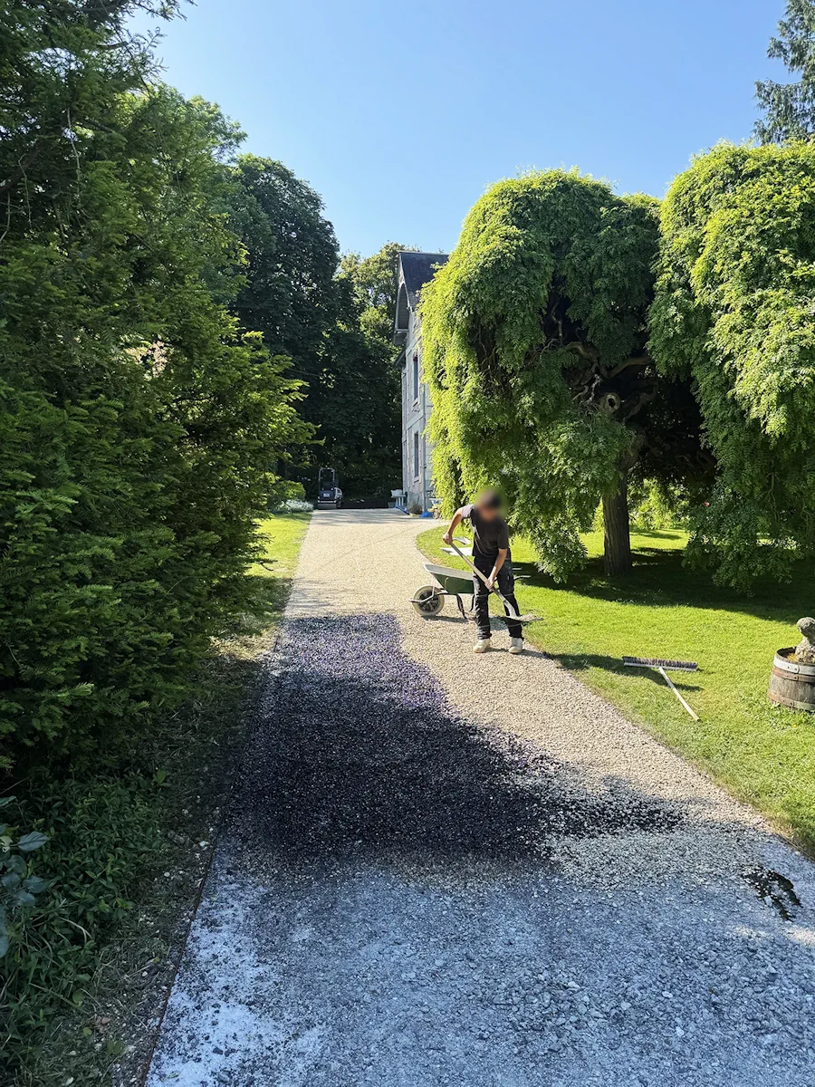 Compagnon égalisant le gravier au râteau sur une allée de propriété
