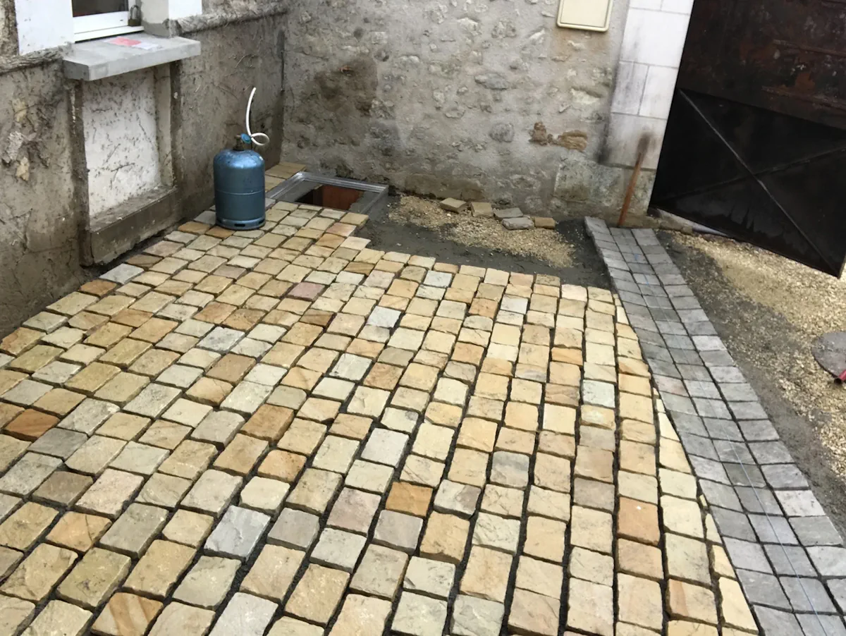 Terrasse en pavés de pierre dorée terminée, bordée d'une rive en pavés gris