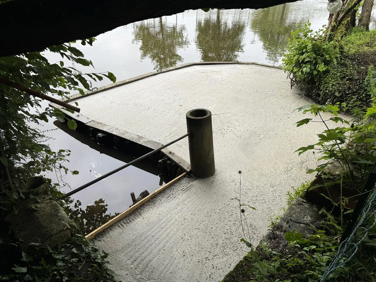 Cale bétonnée avec une bitte d'amarrage en béton, descendant jusqu'à la rivière