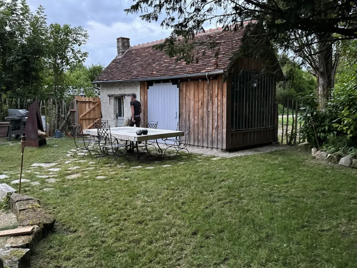 Appentis en bardage bois avec porte coulissante de grange, accolé à une longère de pierre