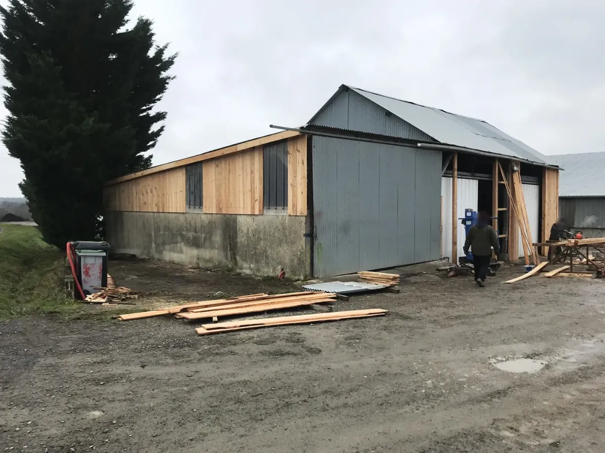 Hangar agricole dont le long pan et le pignon reçoivent un bardage en lames de bois neuves