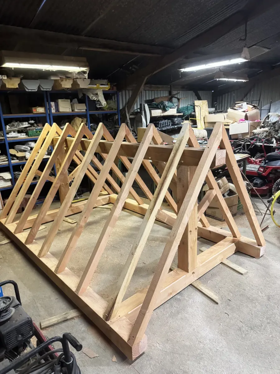 Fermes de charpente en bois alignées dans l'atelier, chevrons en attente de pose