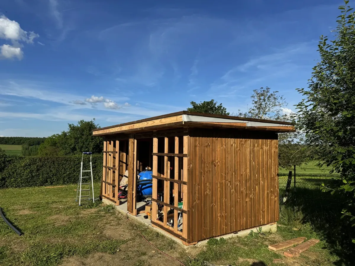 Local technique en cours de bardage, groupe de filtration de piscine visible à l'intérieur