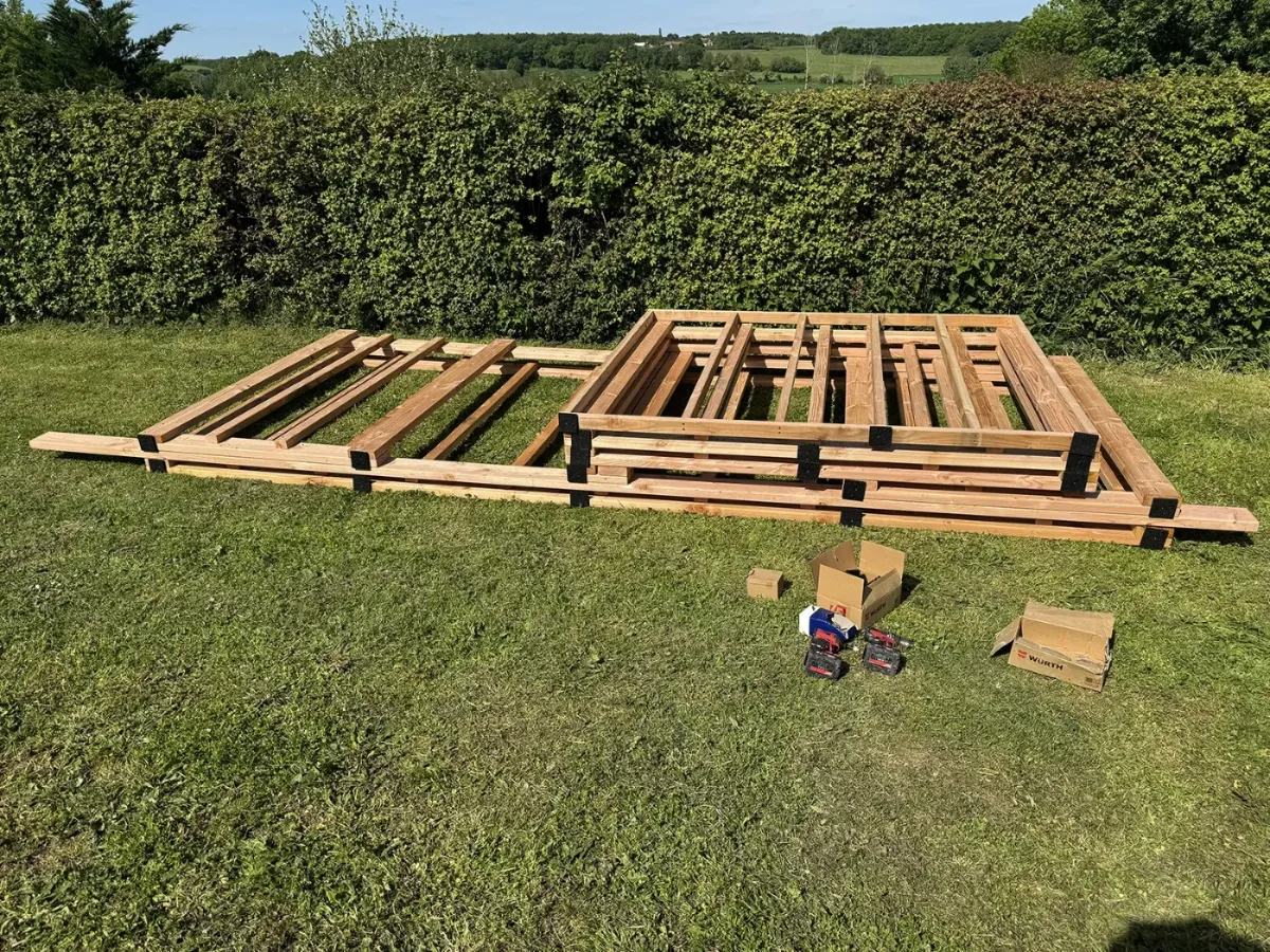 Murs d'ossature bois assemblés à plat sur l'herbe, avant redressement de l'abri