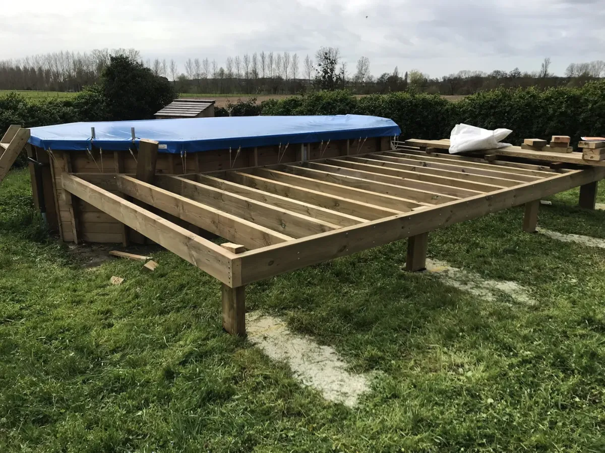 Ossature d'une terrasse de piscine posée sur plots béton, solives en place et lames en attente