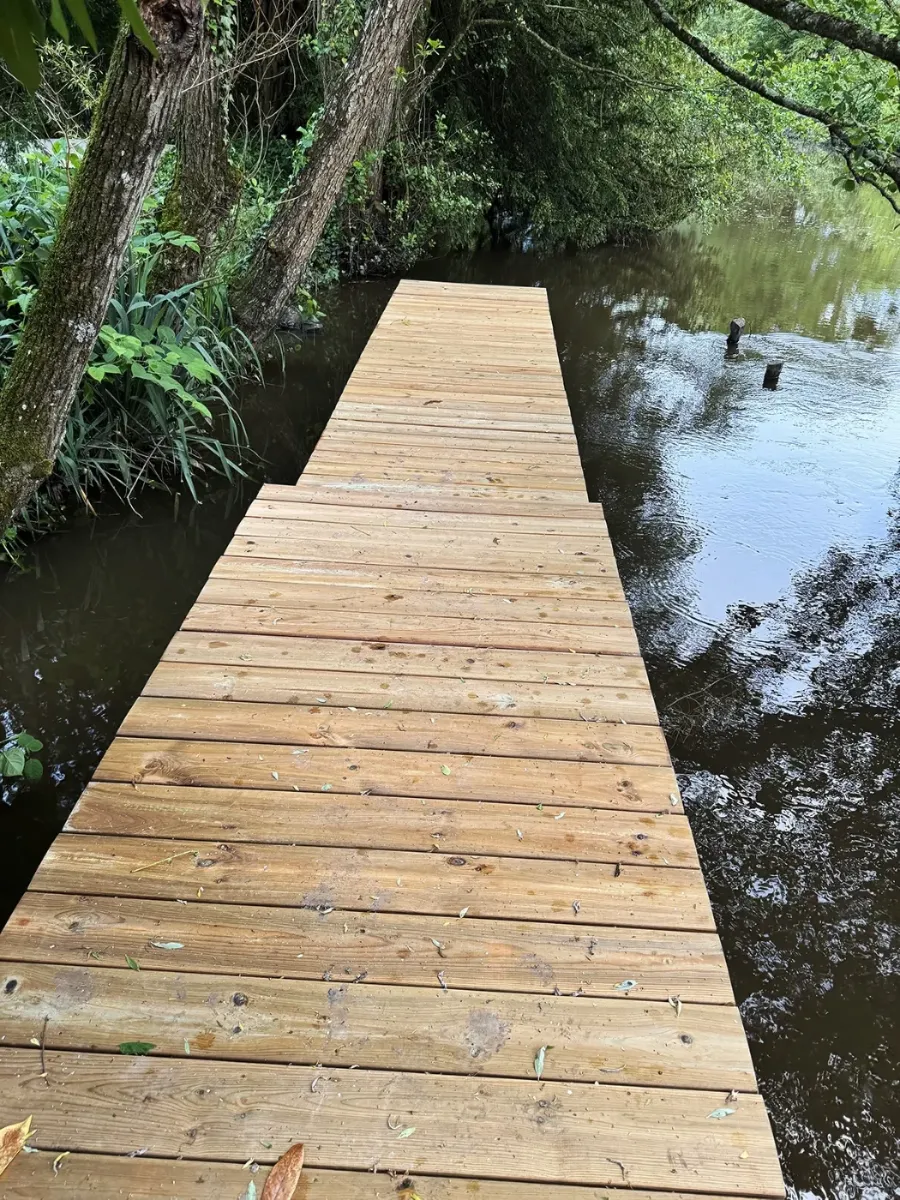 Ponton en bois vu depuis l'amont de la rivière, garde-corps et platelage neufs