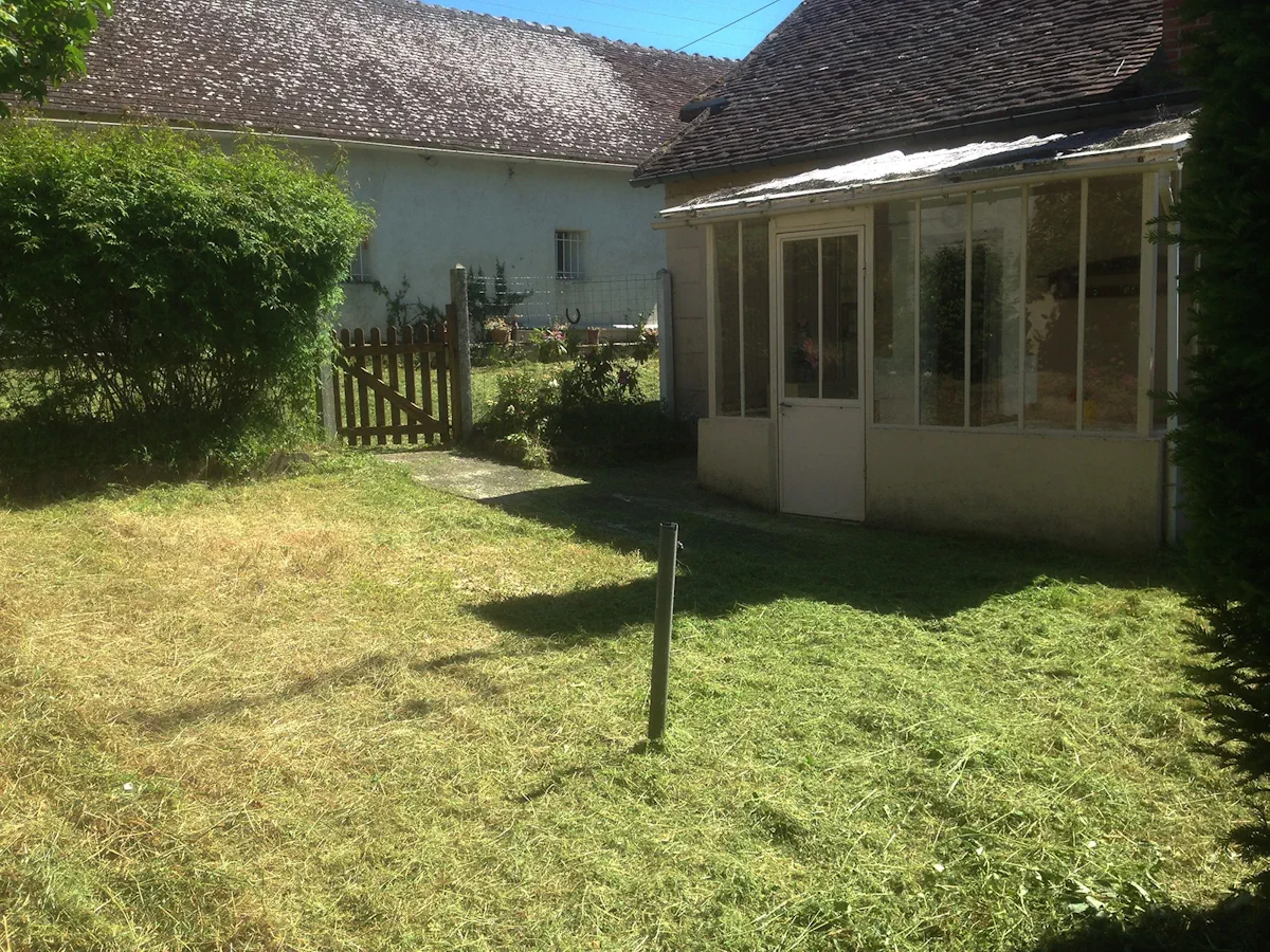 Abords d'une véranda ancienne et d'un portillon de bois dégagés, herbe coupée au sol