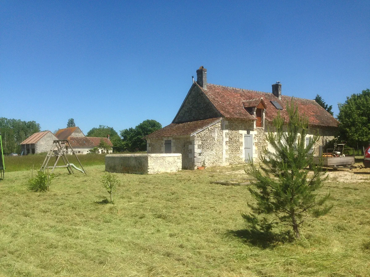 Longère et ses dépendances au milieu d'une prairie fauchée, jeux d'enfants installés