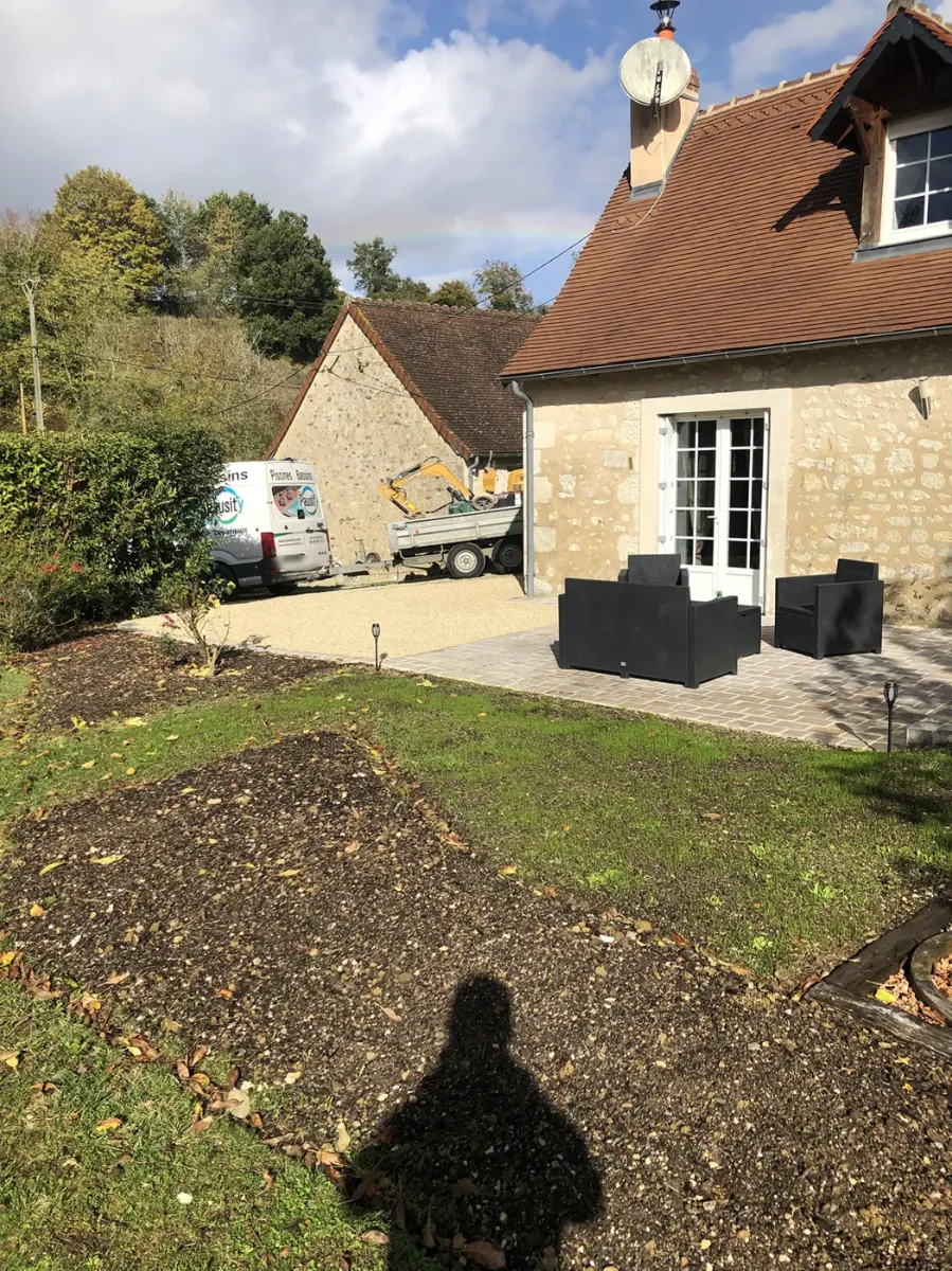 Pelouse en cours de reprise devant une maison de pierre, fourgon Pausity dans la cour