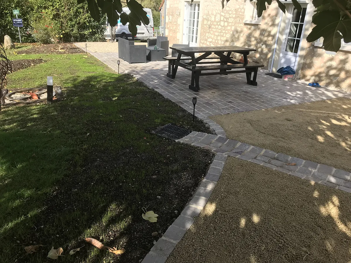 Bande de terre préparée entre une pelouse existante et une terrasse pavée neuve
