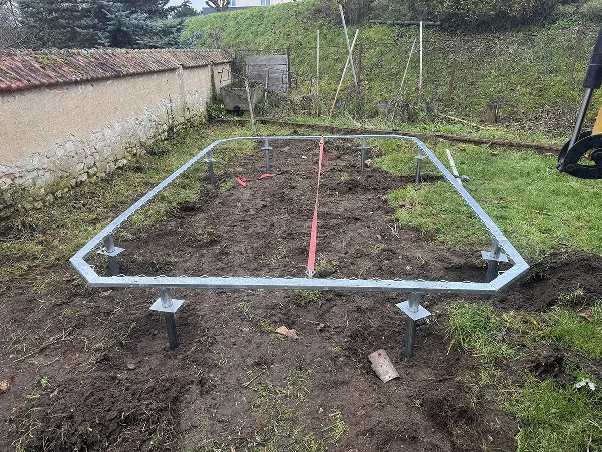 Ossature d'acier galvanisé posée sur plots réglables, mise à niveau au cordeau dans un jardin