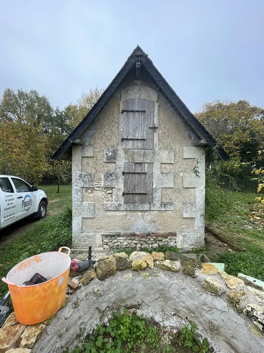 Pignon d'une maisonnette de pierre en cours de restauration, fourgon Pausity et outillage sur place