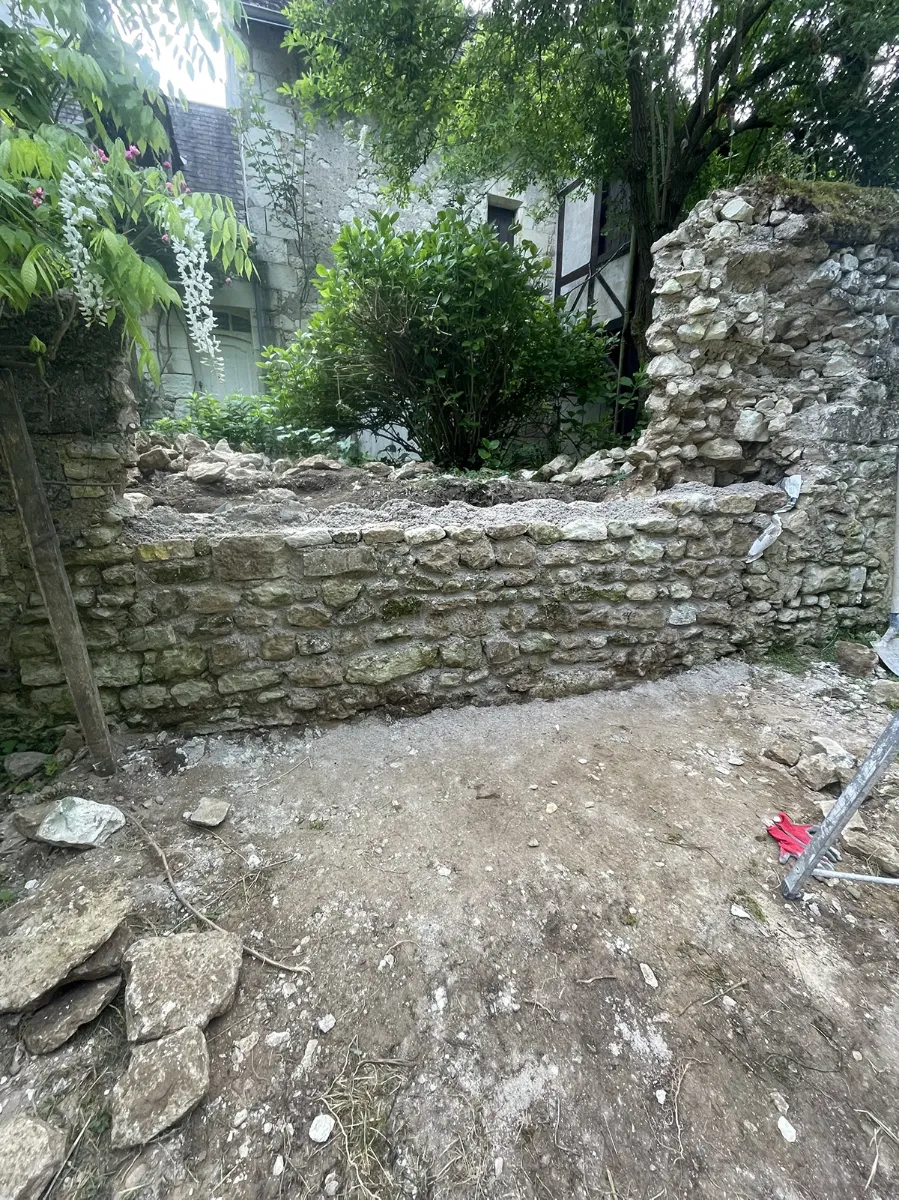 Mur de pierre calcaire remonté à hauteur d'appui, arase en attente, dans un jardin clos