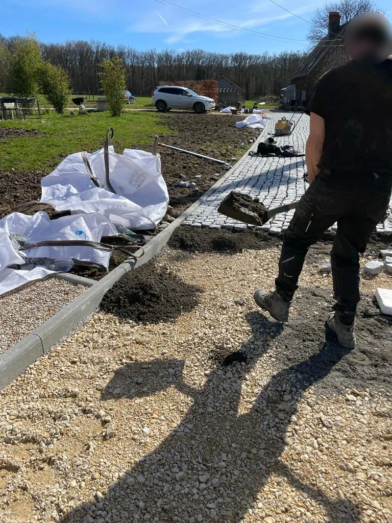 Compagnon apportant le mortier à la pelle le long d'une allée pavée en cours de pose