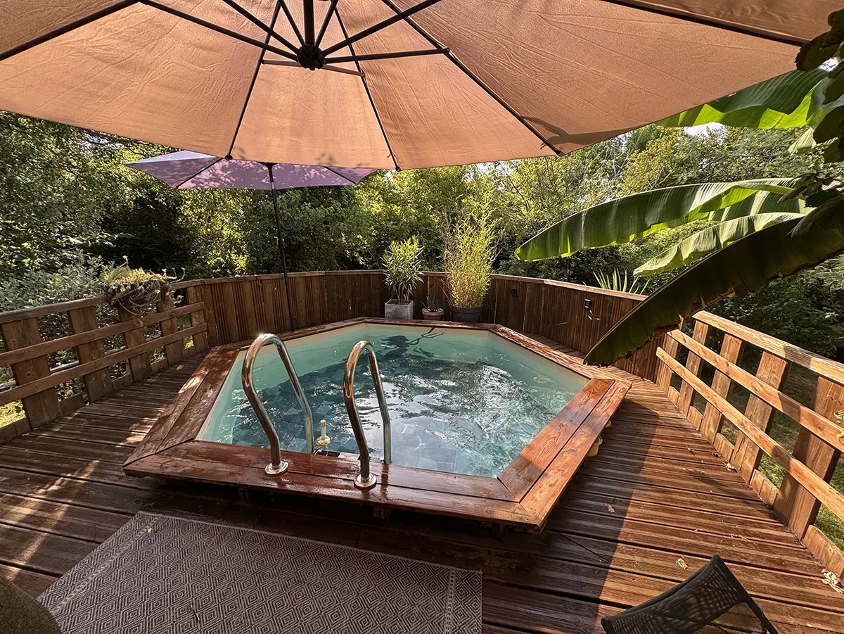Bassin hexagonal et son échelle inox vus depuis la terrasse, sous les parasols