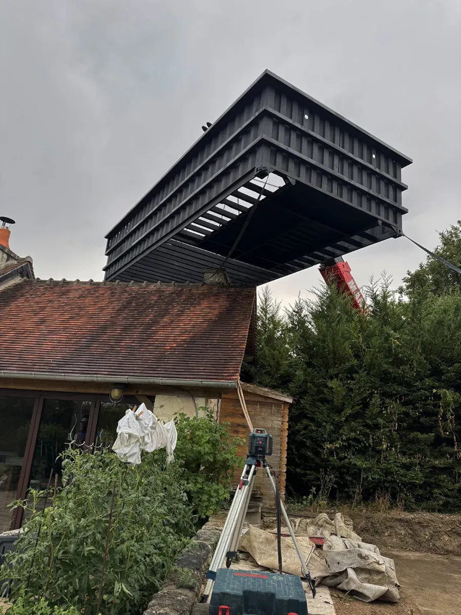 Structure d'acier d'une piscine levée à la grue au-dessus du toit d'une maison, niveau laser au premier plan