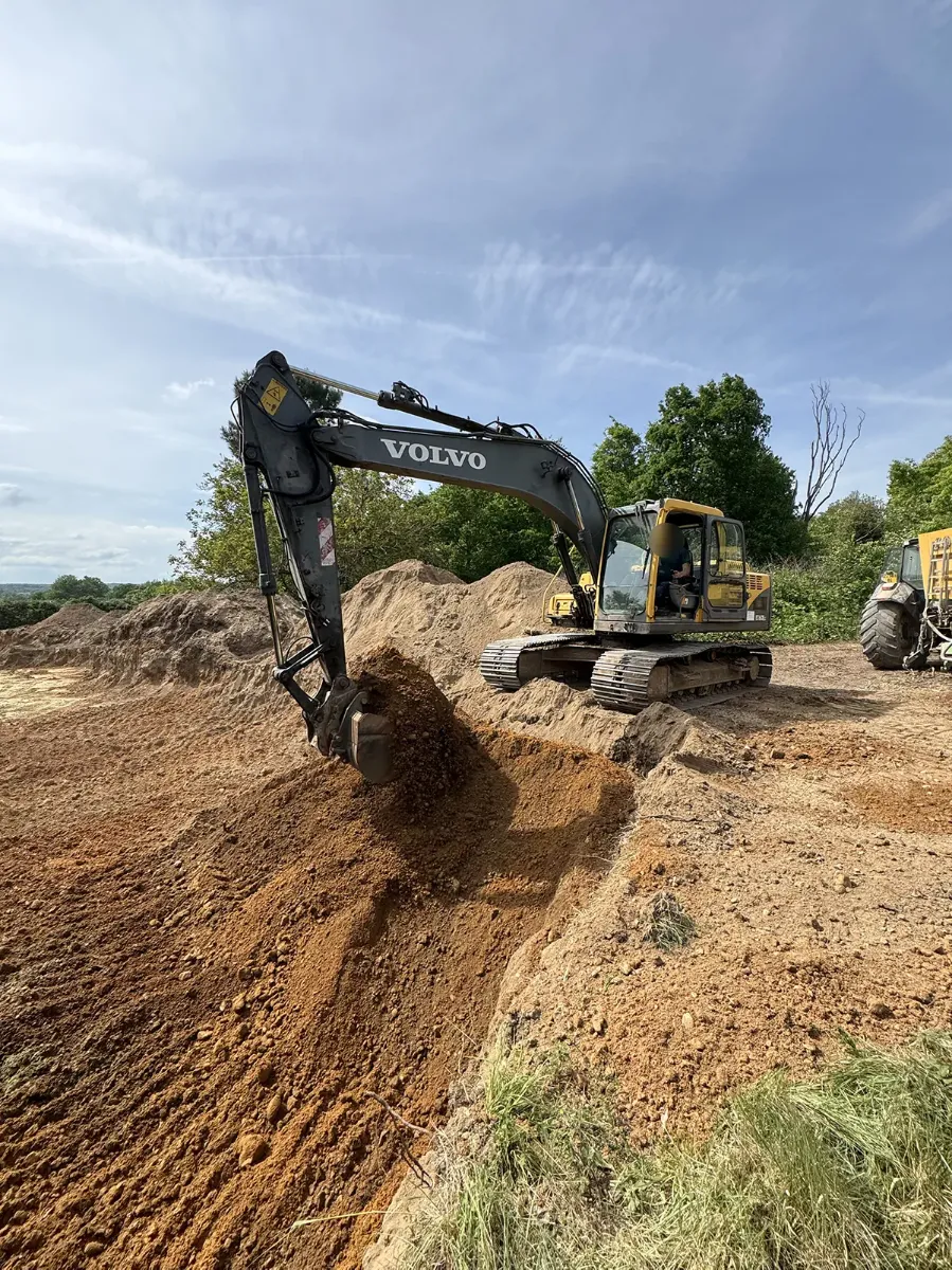 Pelle Volvo déversant un godet de terre ocre sur le front de taille d'un chantier de terrassement