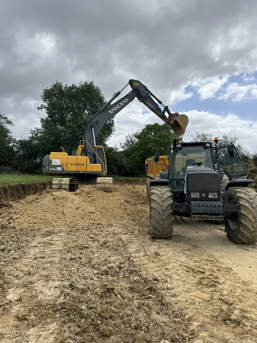 Pelle Volvo posée sur ses plaques et tracteur attelé à une benne, sur une plateforme en cours de terrassement