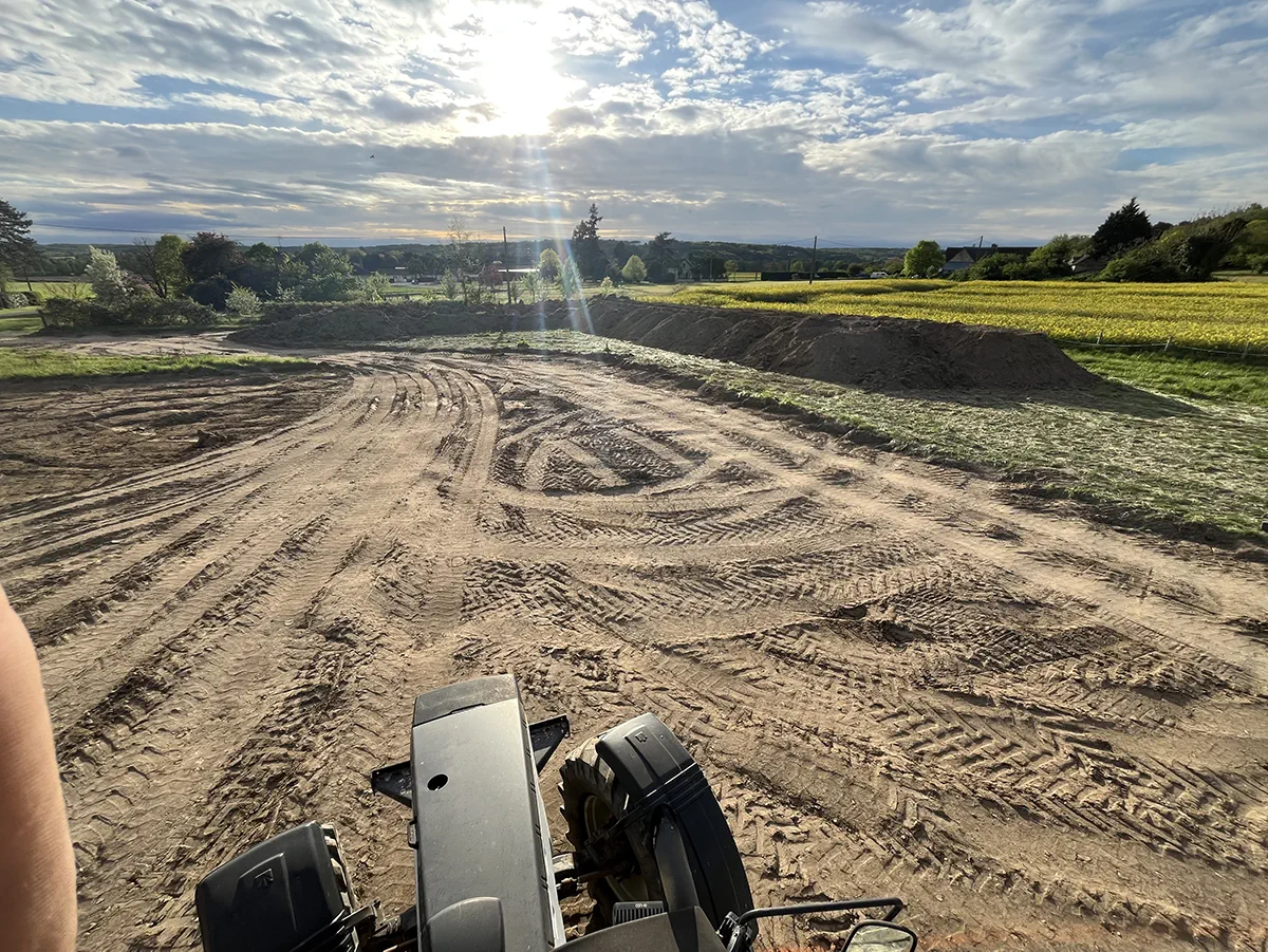 Plateforme nivelée portant les traces de roues, vue depuis la cabine d'un engin, à contre-jour